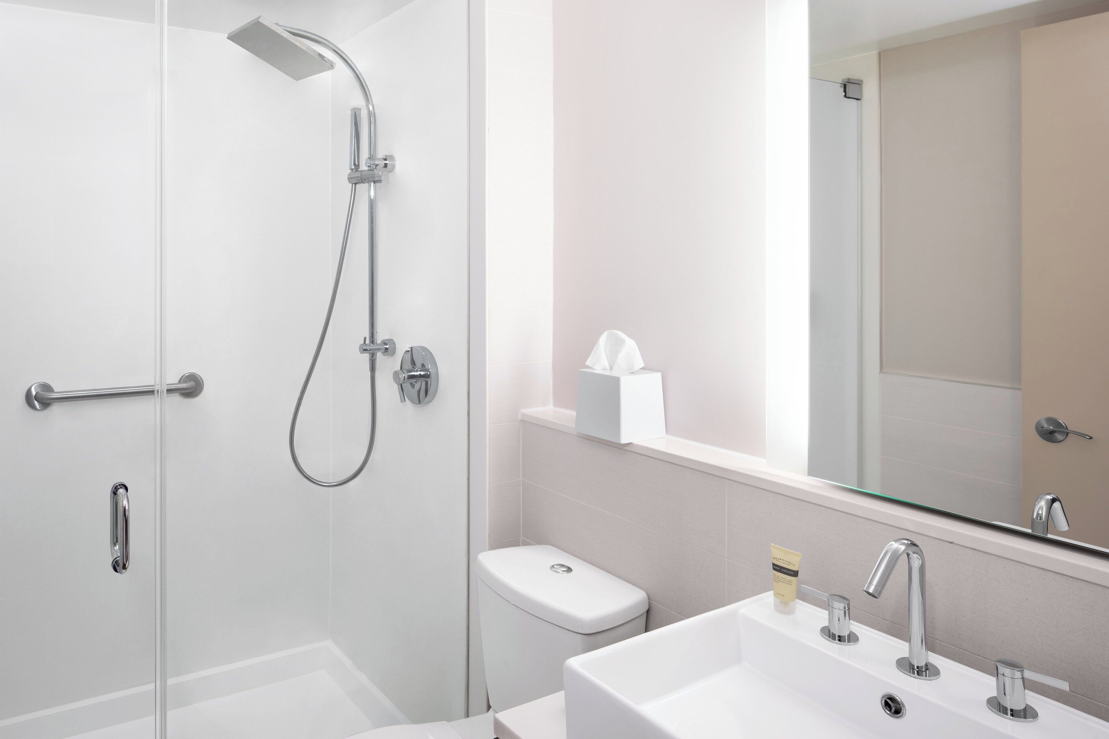 Une salle de bain moderne avec une douche à parois de verre, des toilettes, un lavabo avec un miroir et un porte-serviettes.