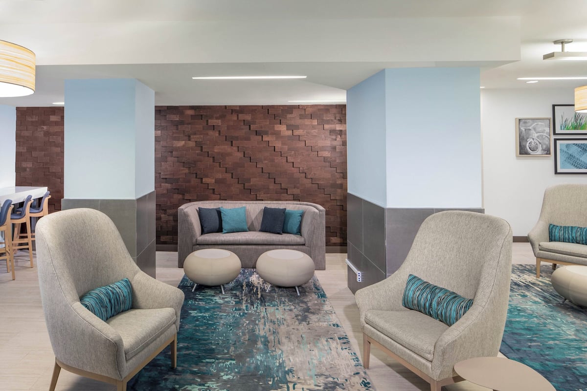 A lobby with two armchairs, a sofa, and a patterned rug.