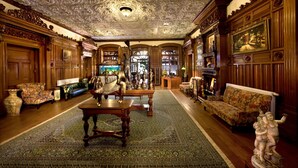 An opulent room with ornate wood paneling, a large ornate ceiling, and a grand fireplace.