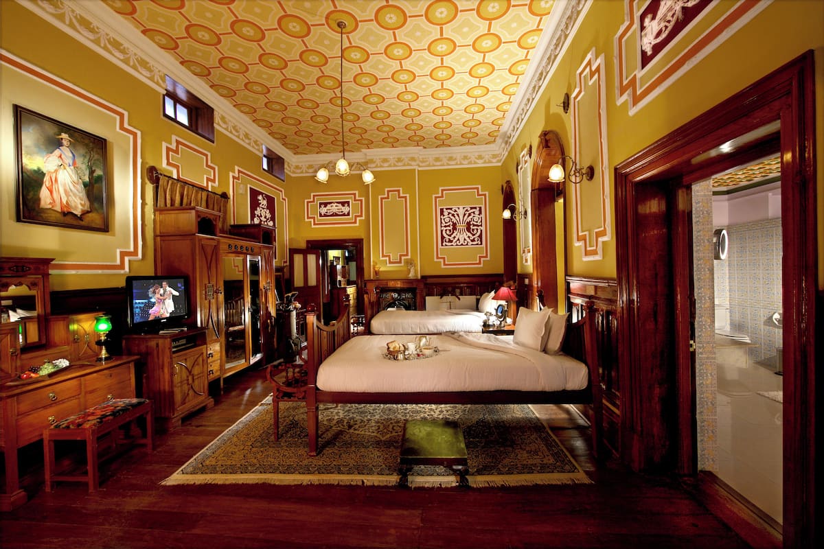 Una habitación tradicional con cama, televisión y aparador de madera.