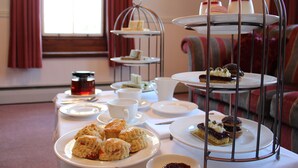 A tea service setup with multiple tea cups, saucers, and a tiered dessert stand. - Woodlands Country House (Wigton)