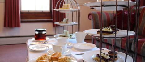 A tea service setup with multiple tea cups, saucers, and a tiered dessert stand.