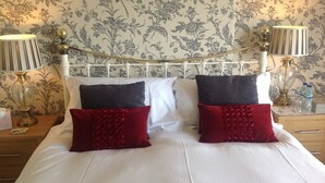 A neatly made bed with white and dark red pillows, a white headboard, and two bedside lamps. - Yacht Bay View (Morecambe)