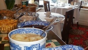 A dining area with a table set for two, featuring a patterned tablecloth, a vase with flowers, and a bowl of food. - Yacht Bay View (Morecambe)