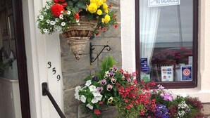 A building with a 'NO VACANCIES' sign, flower baskets, and a 'Support our Lifeboats' sticker. - Yacht Bay View (Morecambe)