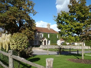 A stone building with a green ivy-covered wall, a traditional brick roof, and a paved driveway. - Manor Farm B & B (Marlborough)