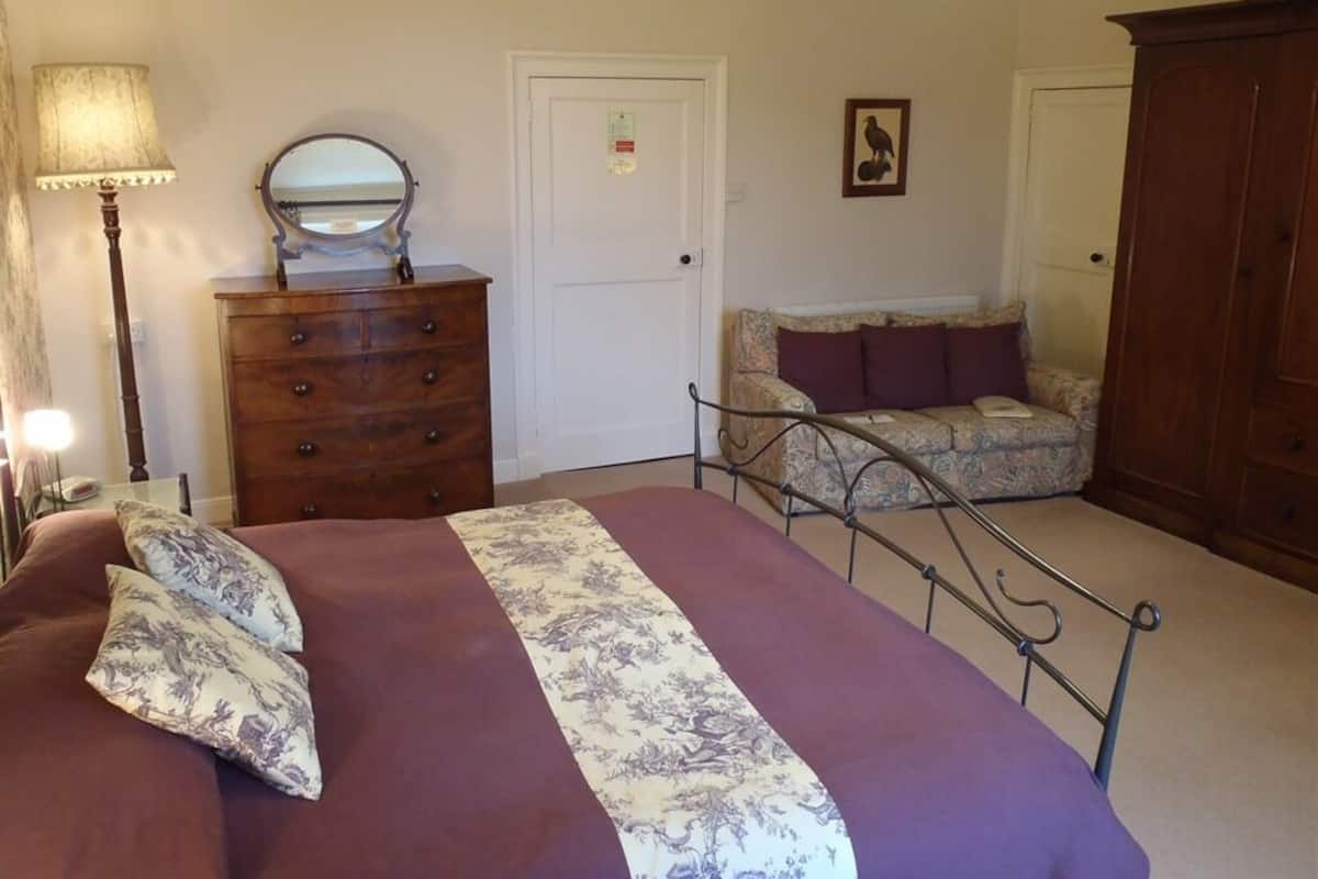 A bedroom with a bed, dresser, and a chair.