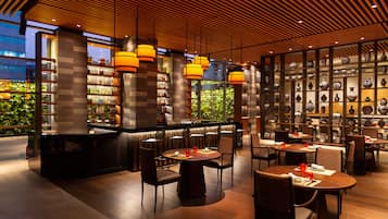 Un área de bar moderna con techo de madera, taburetes y una exhibición de jarrones.
