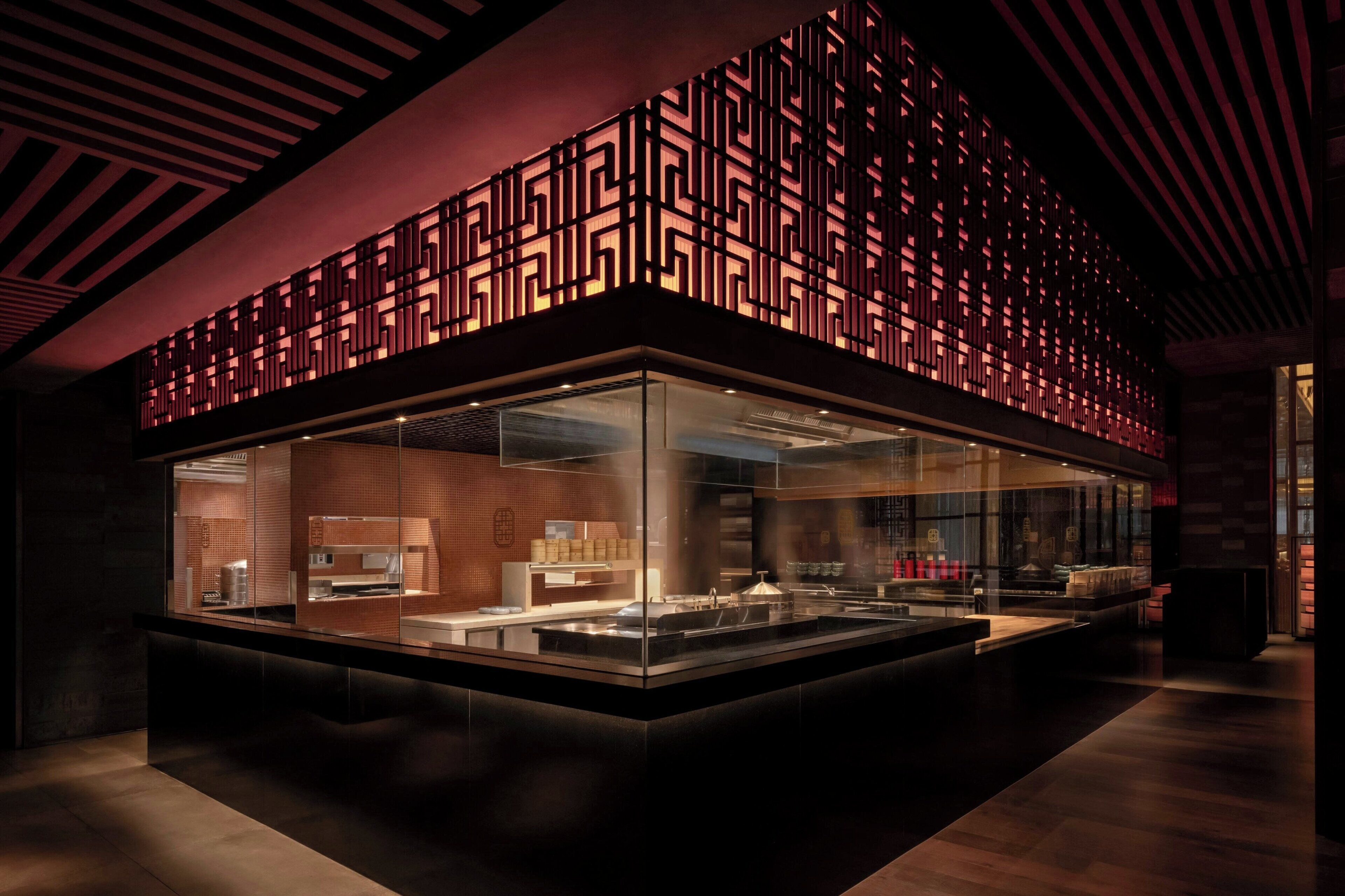 A modern restaurant with a glass enclosure and a geometric patterned ceiling.
