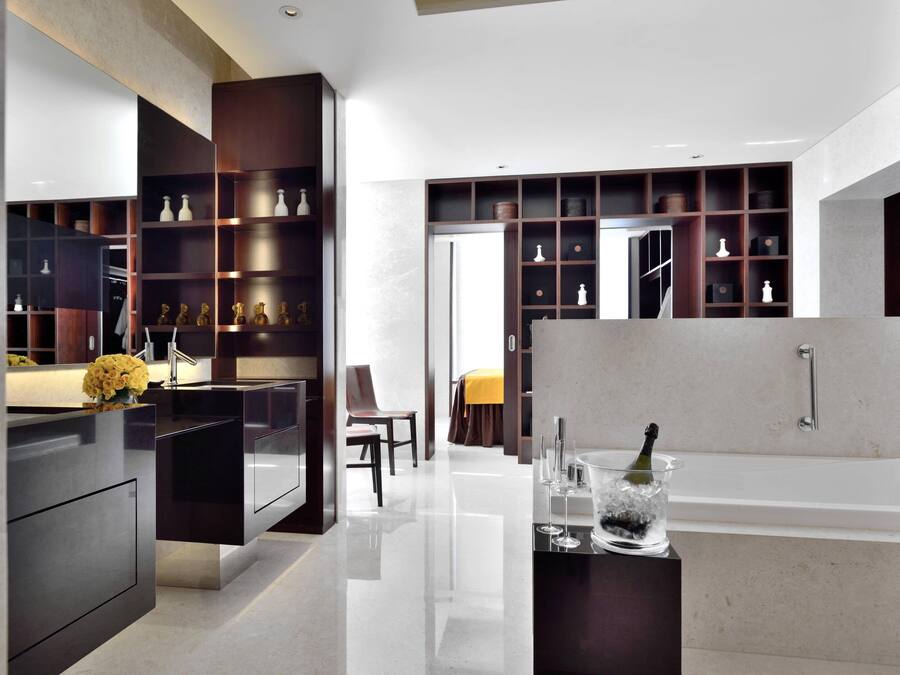 A modern bathroom with a large bathtub, a vanity with a mirror, and a shelf with decorative items.