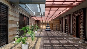 A corridor with a tiled floor, potted plants, and decorative stone elements.