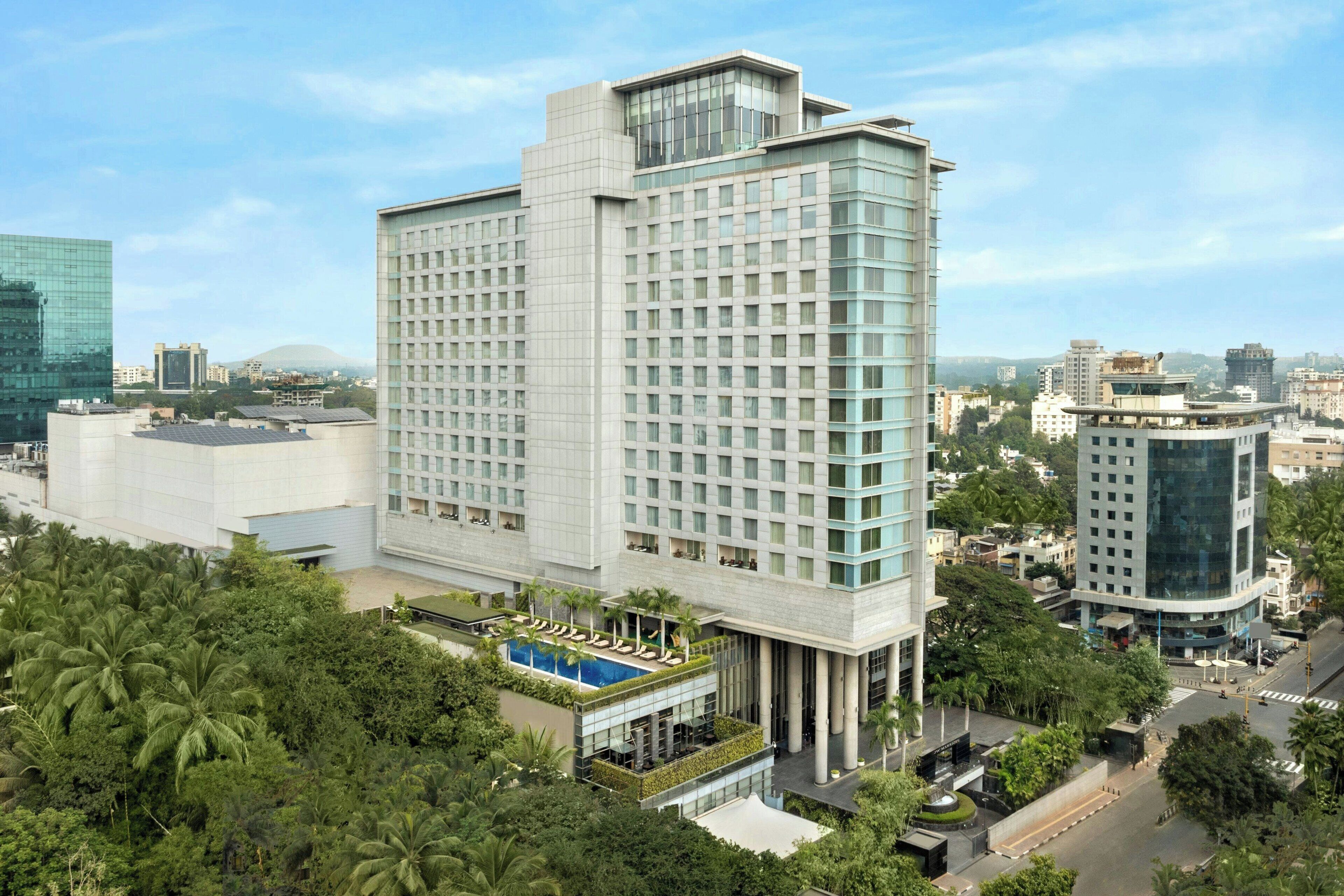 A modern hotel with a central courtyard, large windows, and a pool area.