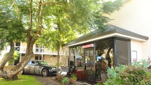A building with a reception area, a parked car, and a tree in front. - Auckland Newmarket Motel (Auckland)