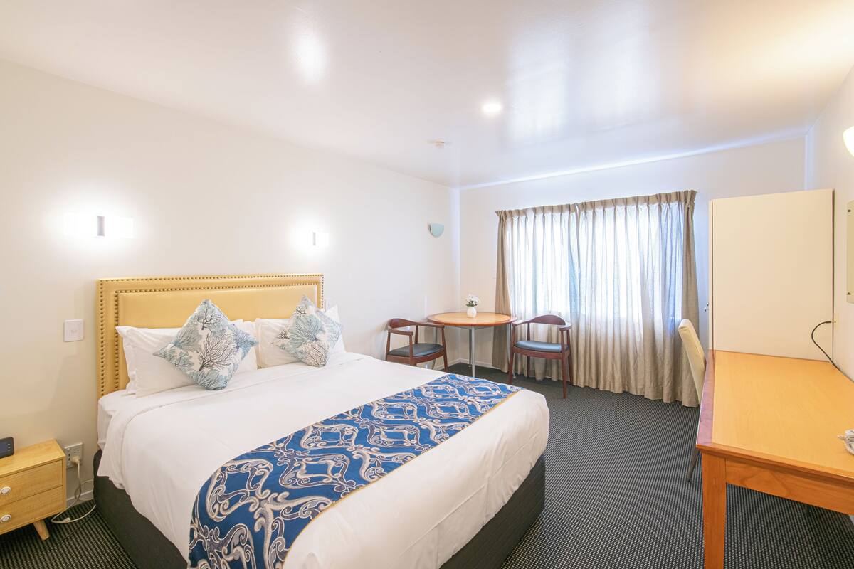 A hotel room with a large bed, a desk, and a chair.
