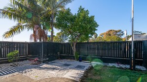 A fenced backyard with a paved patio, gravel area, and small plants. - Auckland Newmarket Motel (Auckland)
