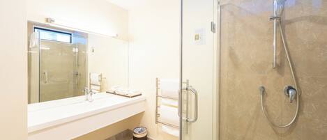 Un bagno moderno con box doccia in vetro, lavandino bianco e porta asciugamani.