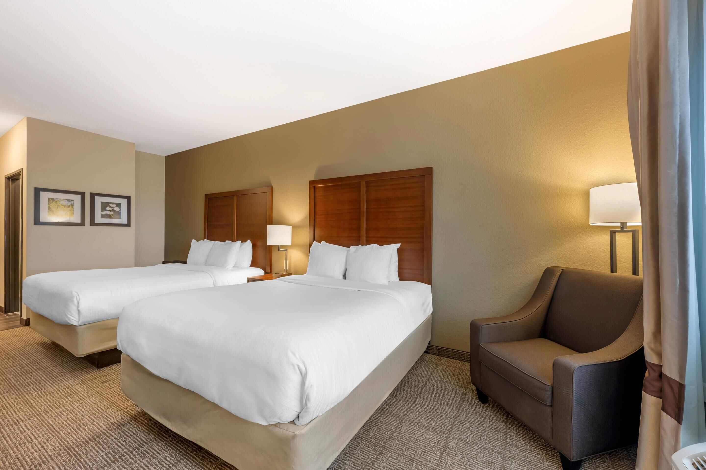 A hotel room with two single beds, a sofa, and a lamp.