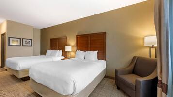 A hotel room with two single beds, a sofa, and a lamp.