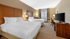 A hotel room with two beds, a desk, a television, and a large window with curtains. - Comfort Inn I-20 Midland Stanton (Stanton)