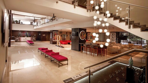 A spacious hotel lobby with a modern staircase, seating areas, and a reception desk. - Renaissance Caracas La Castellana Hotel (Caracas)
