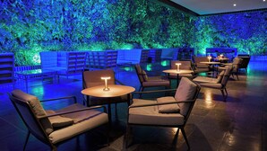 A modern lounge area with seating and tables, a green wall with plants, and ambient lighting. - Renaissance Caracas La Castellana Hotel (Caracas)