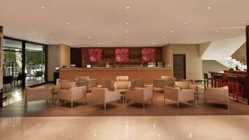 A spacious lobby with a bar area, seating arrangements, and a view of the outdoors.