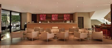 A spacious lobby with a bar area, seating arrangements, and a view of the outdoors.