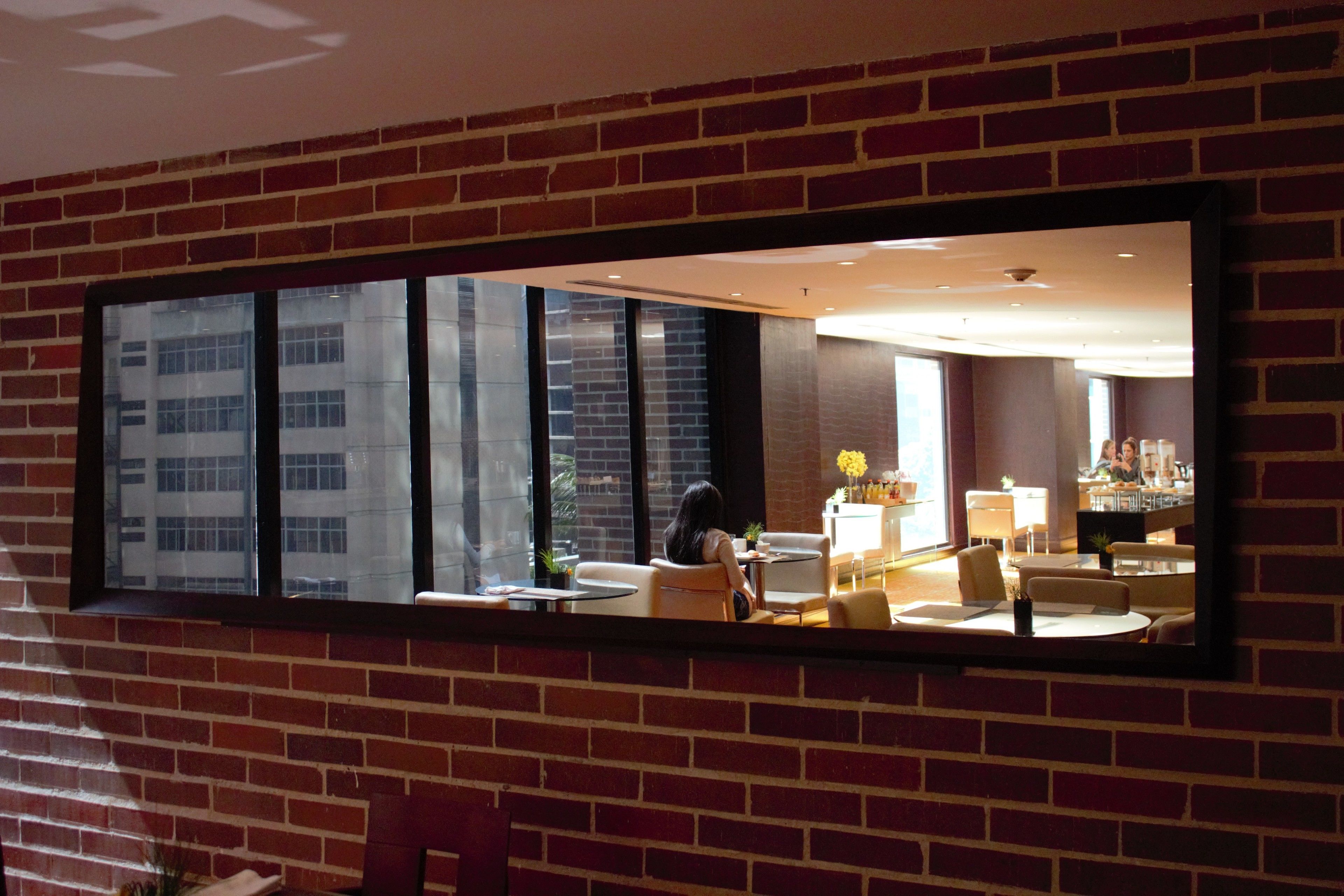 A room with a brick wall, large windows, and a seating area with tables and chairs.