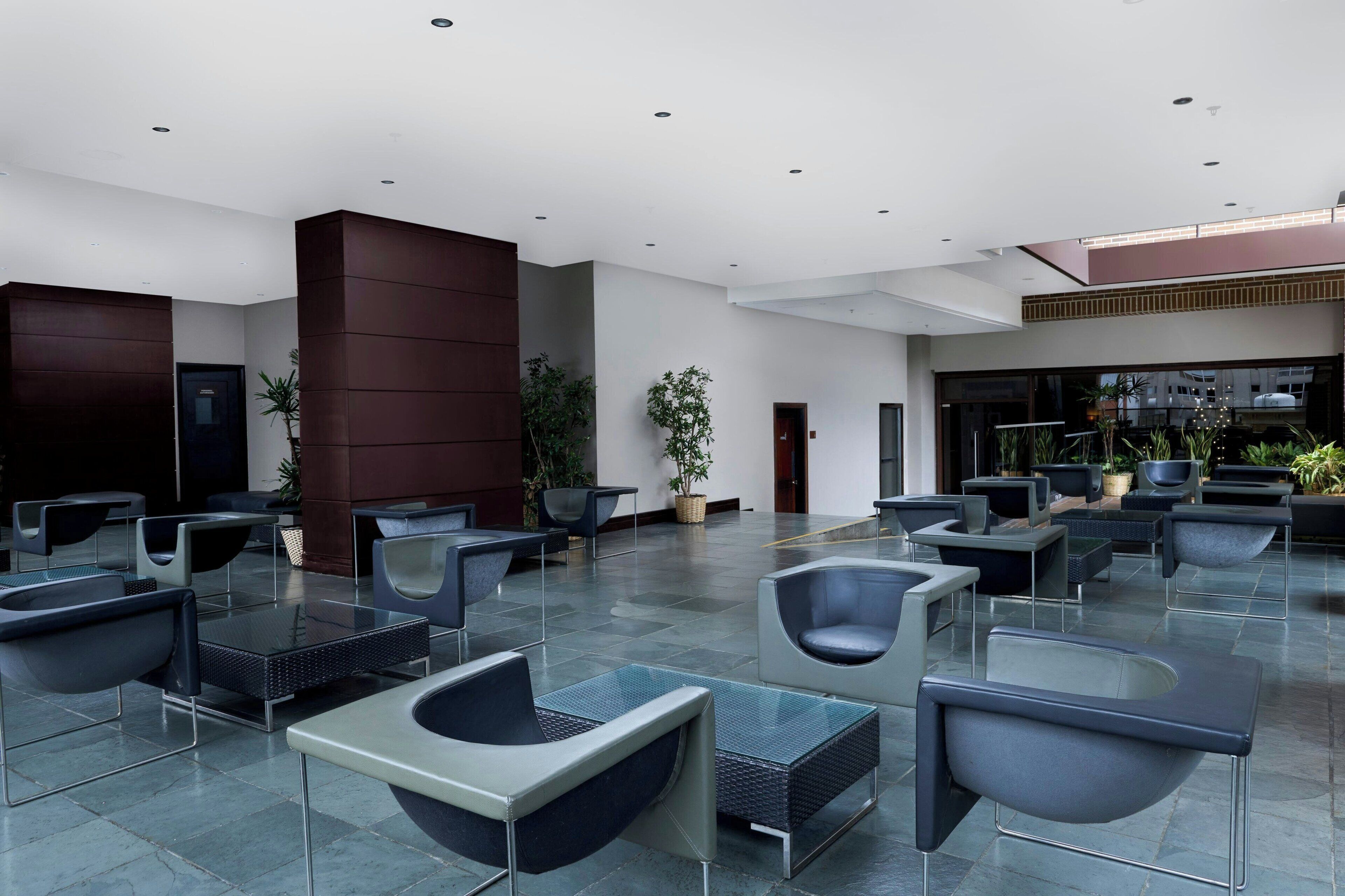 A spacious lobby with modern seating, a reception area, and potted plants.