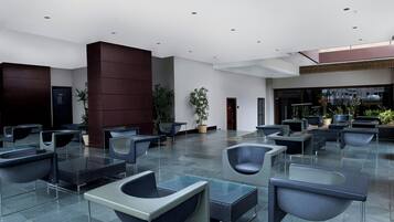 A spacious lobby with modern seating, a reception area, and potted plants.