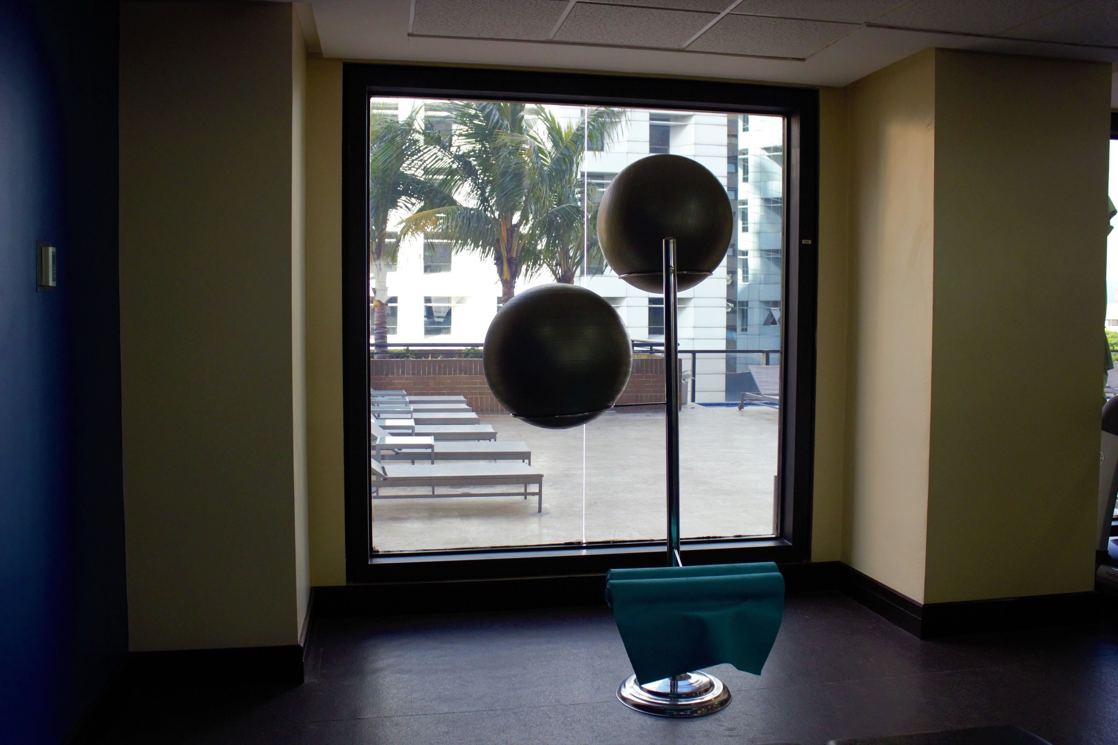 Zona de espera con un amplio ventanal, un banco y una escultura moderna.