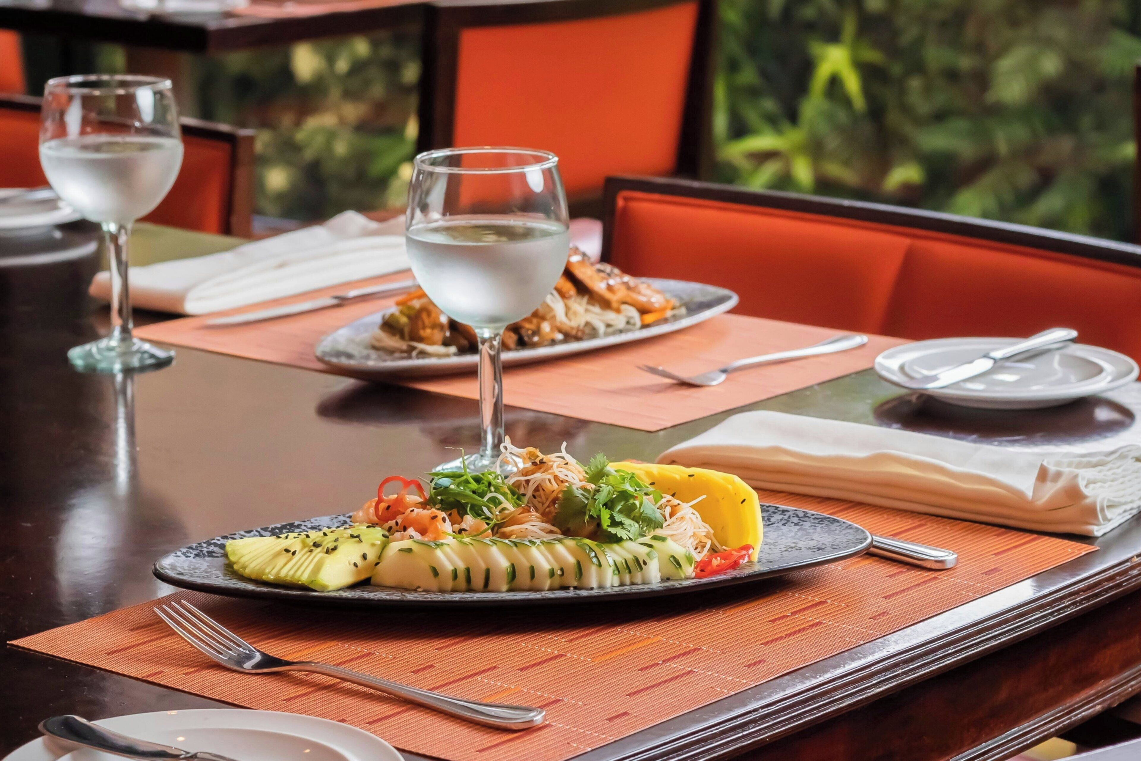Een eettafel met een bord eten, een glas water en bestek.