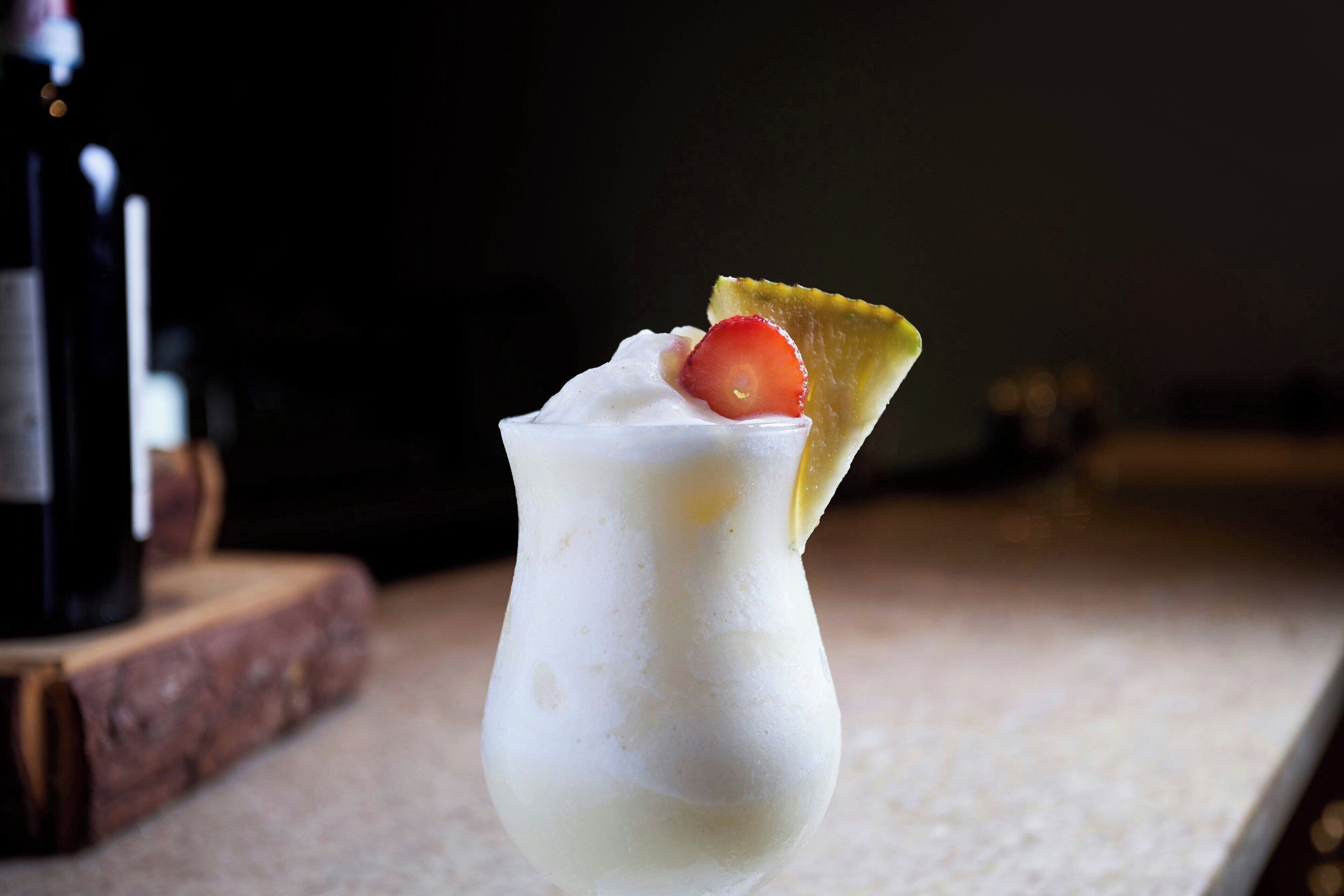 Un postre en vaso con crema batida y una fresa encima.