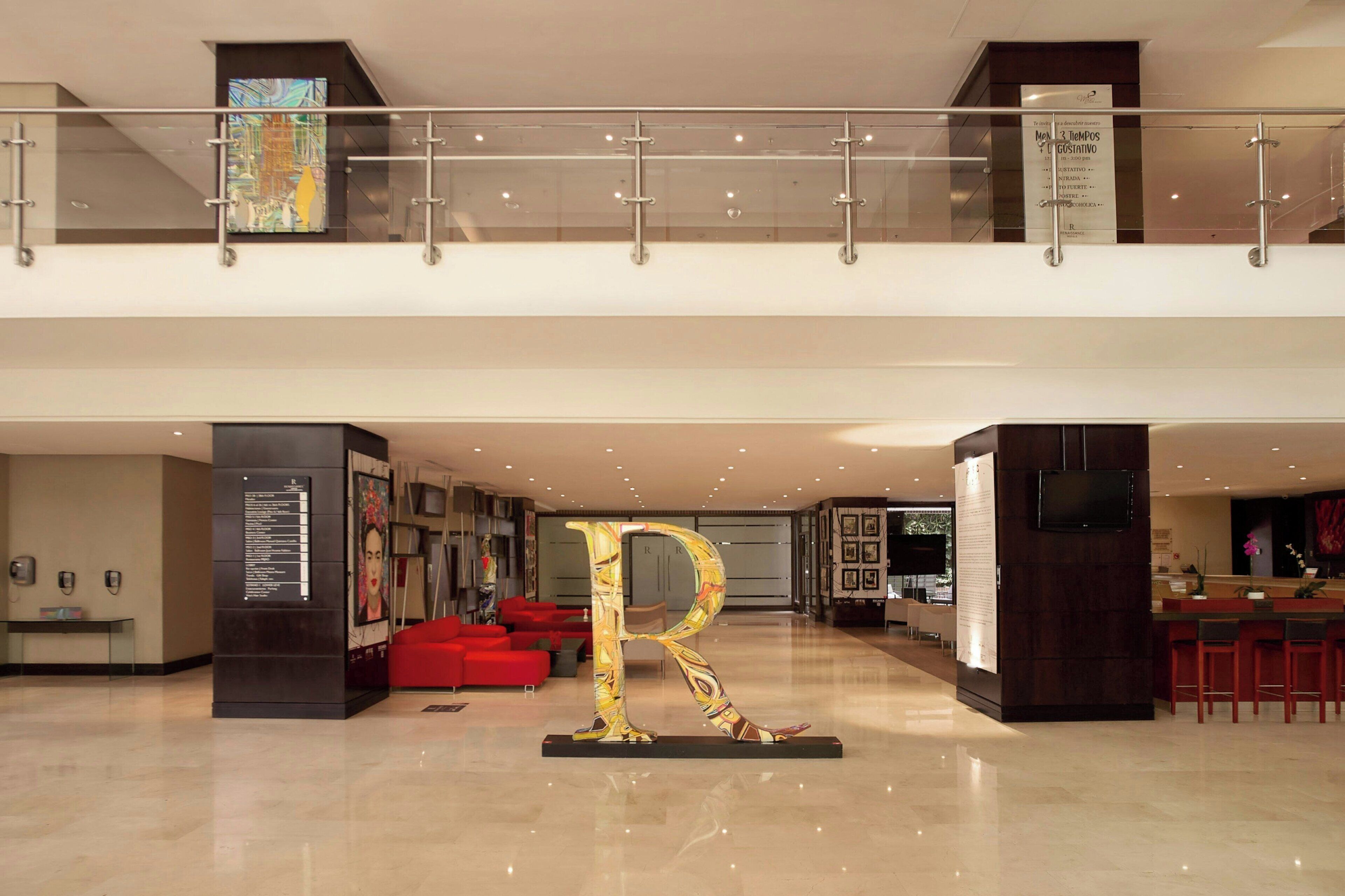 Un hall d’entrée spacieux, agrémenté d’une grande sculpture en forme de « R », de sièges rouges et d’un design moderne.