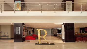 Un hall d’entrée spacieux, agrémenté d’une grande sculpture en forme de « R », de sièges rouges et d’un design moderne.