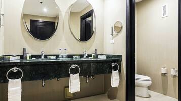 A modern bathroom with two sinks, a toilet, and two large mirrors.