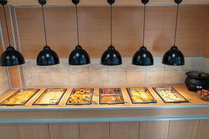 A buffet counter with multiple food trays and a slow cooker. - Creta Aquamarine hotel (Rethymno)