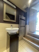 Un baño con un lavamanos blanco, un espejo y un perchero para toallas.
