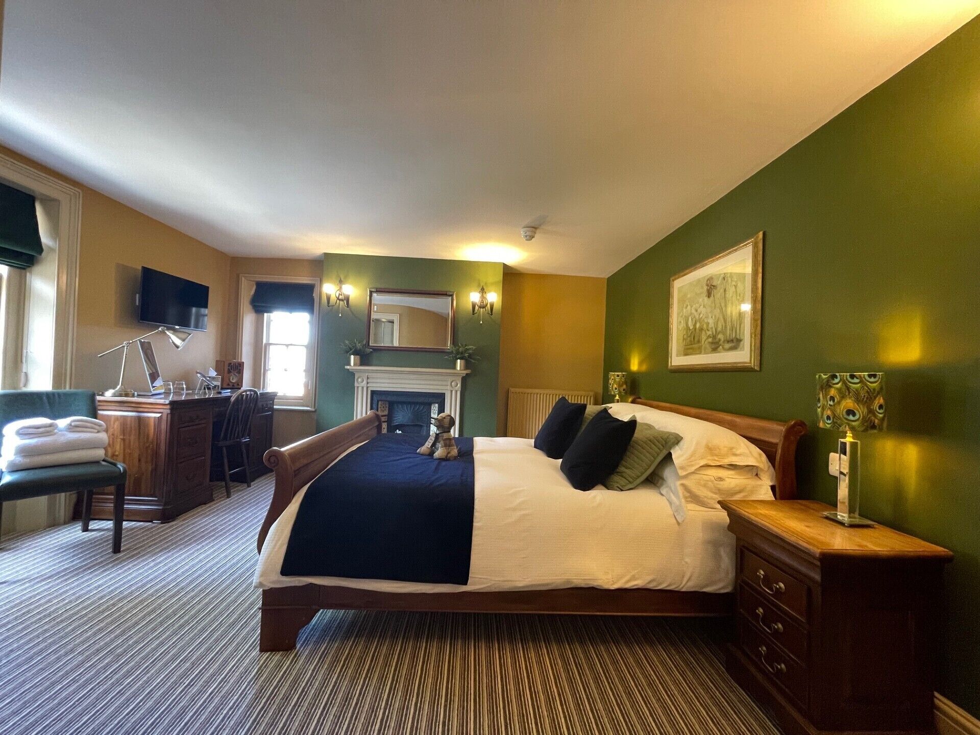 Habitación de hotel con una cama grande, un escritorio con silla, chimenea y televisor.
