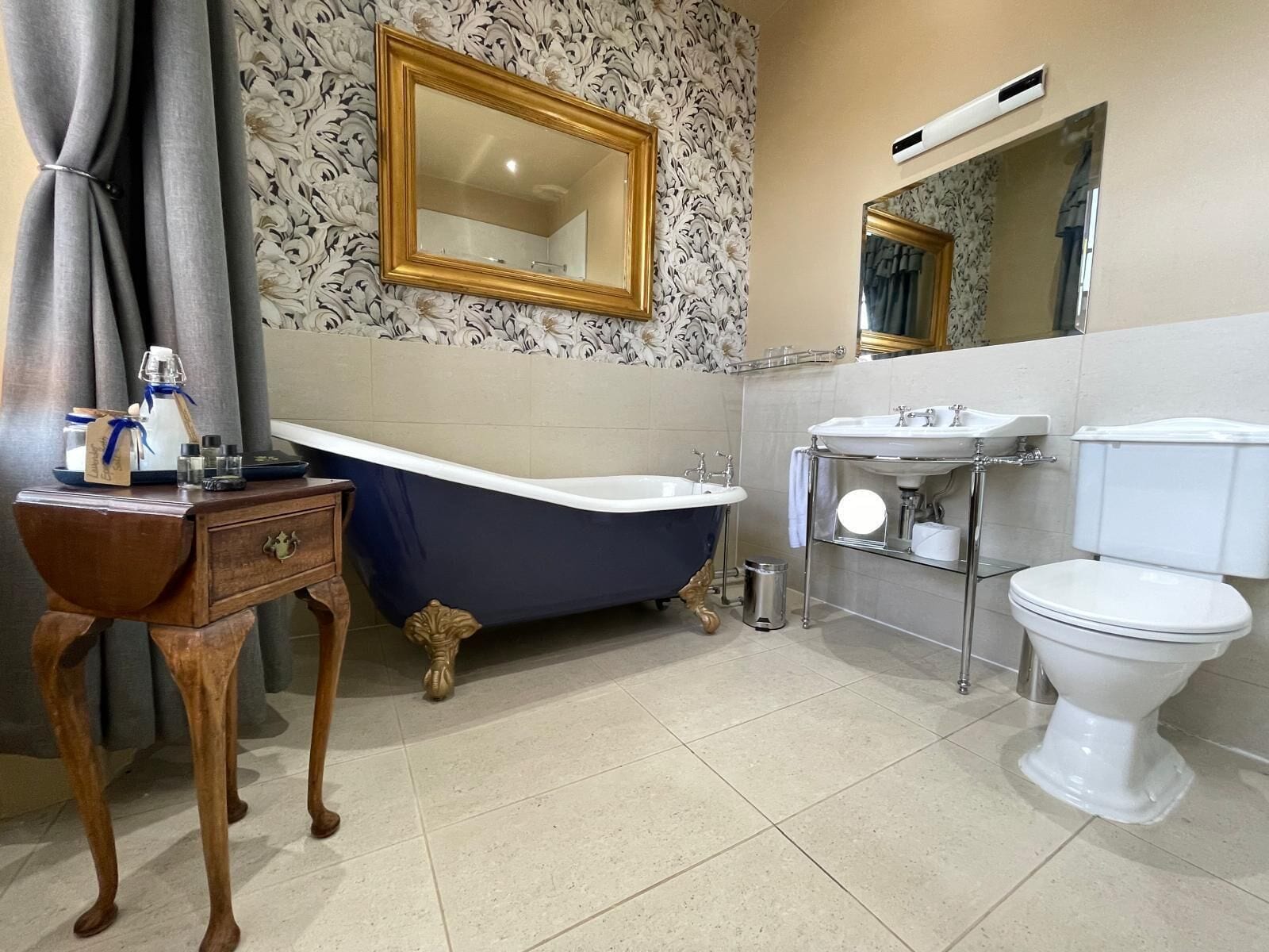 A bathroom with a freestanding bathtub, a vanity with a mirror, a sink, and a toilet.