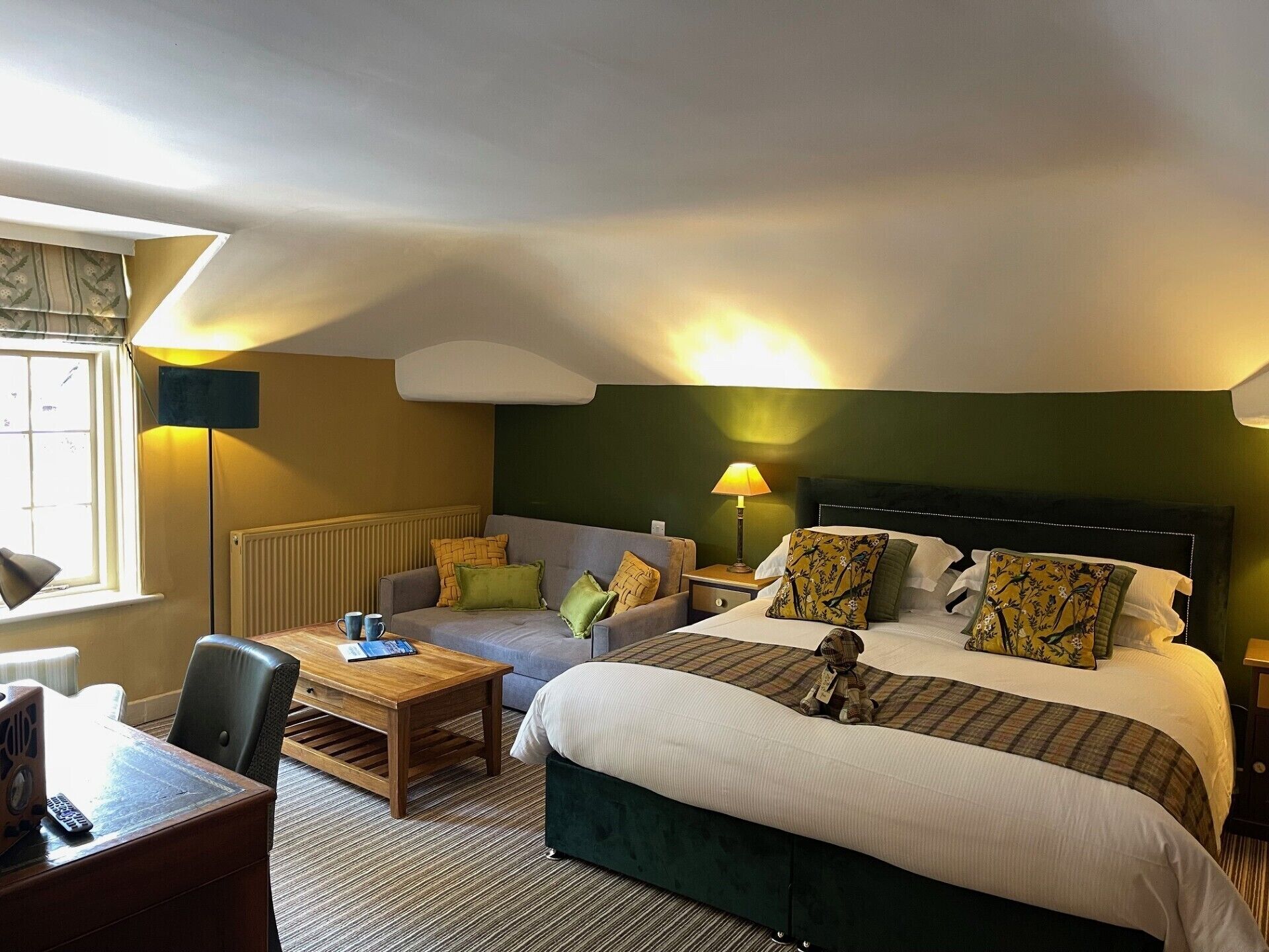 Una habitación de hotel con cama, sofá, escritorio y lámpara.