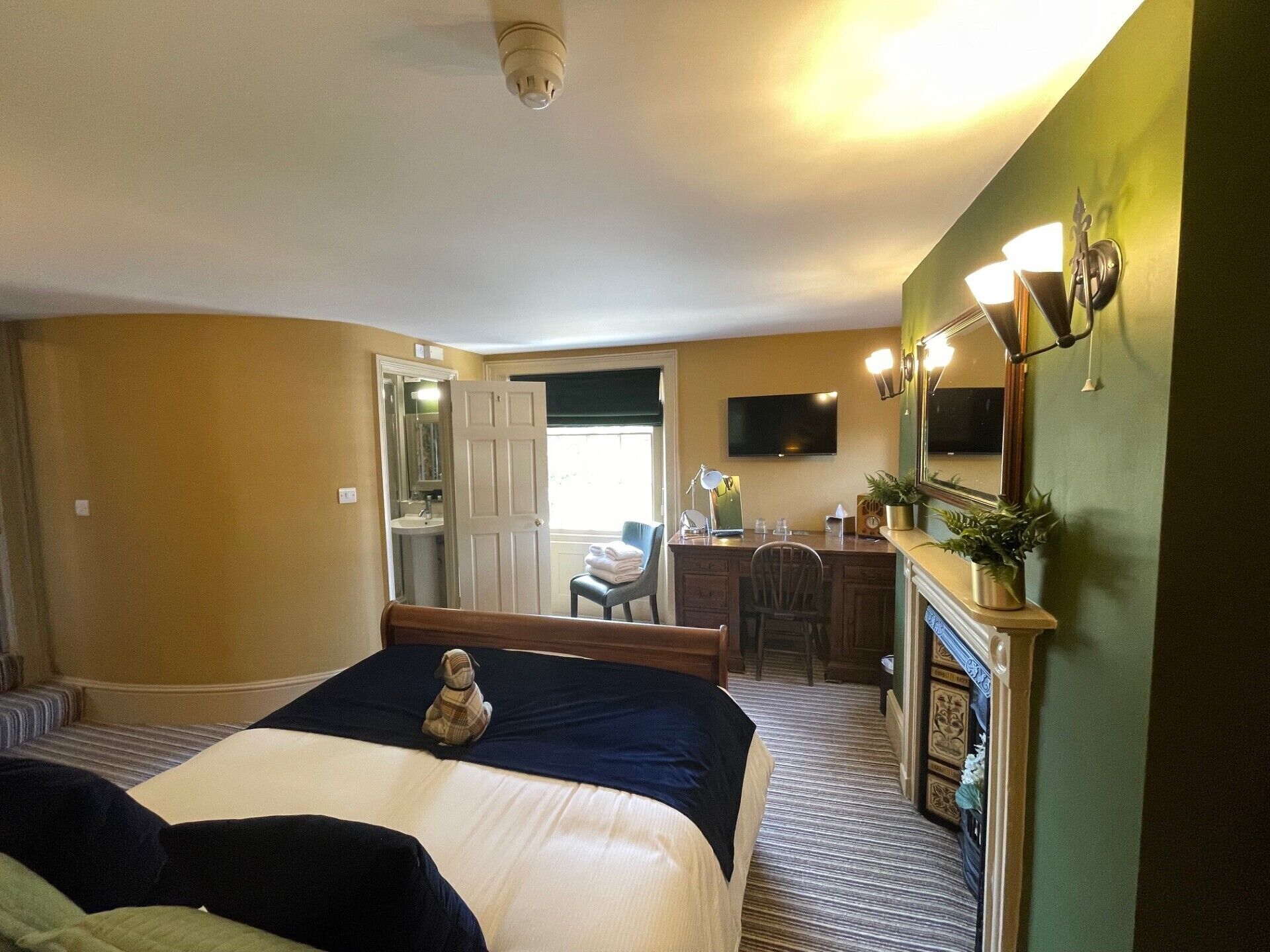 Une chambre d’hôtel équipée d’un lit, d’un bureau, d’une chaise, d’une télévision et d’une cheminée.