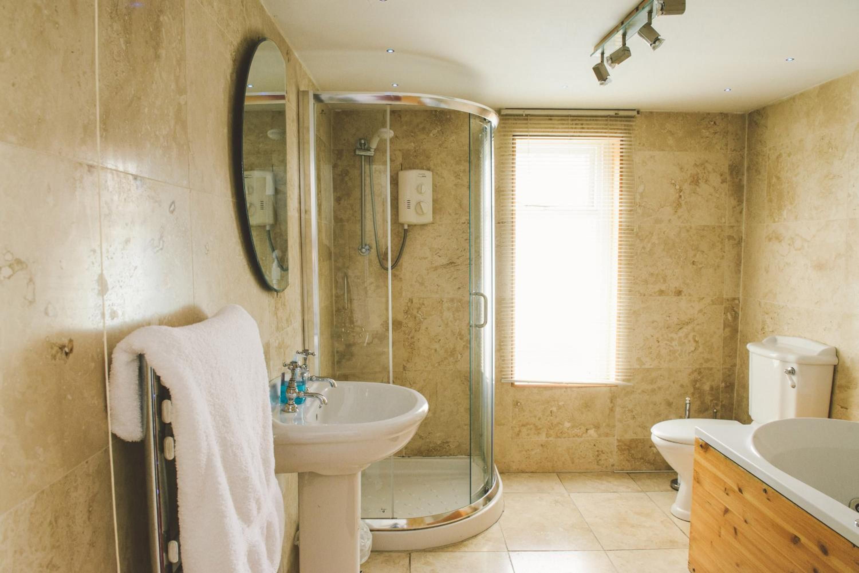 A bathroom with a glass shower enclosure, a sink, a toilet, and a bathtub.