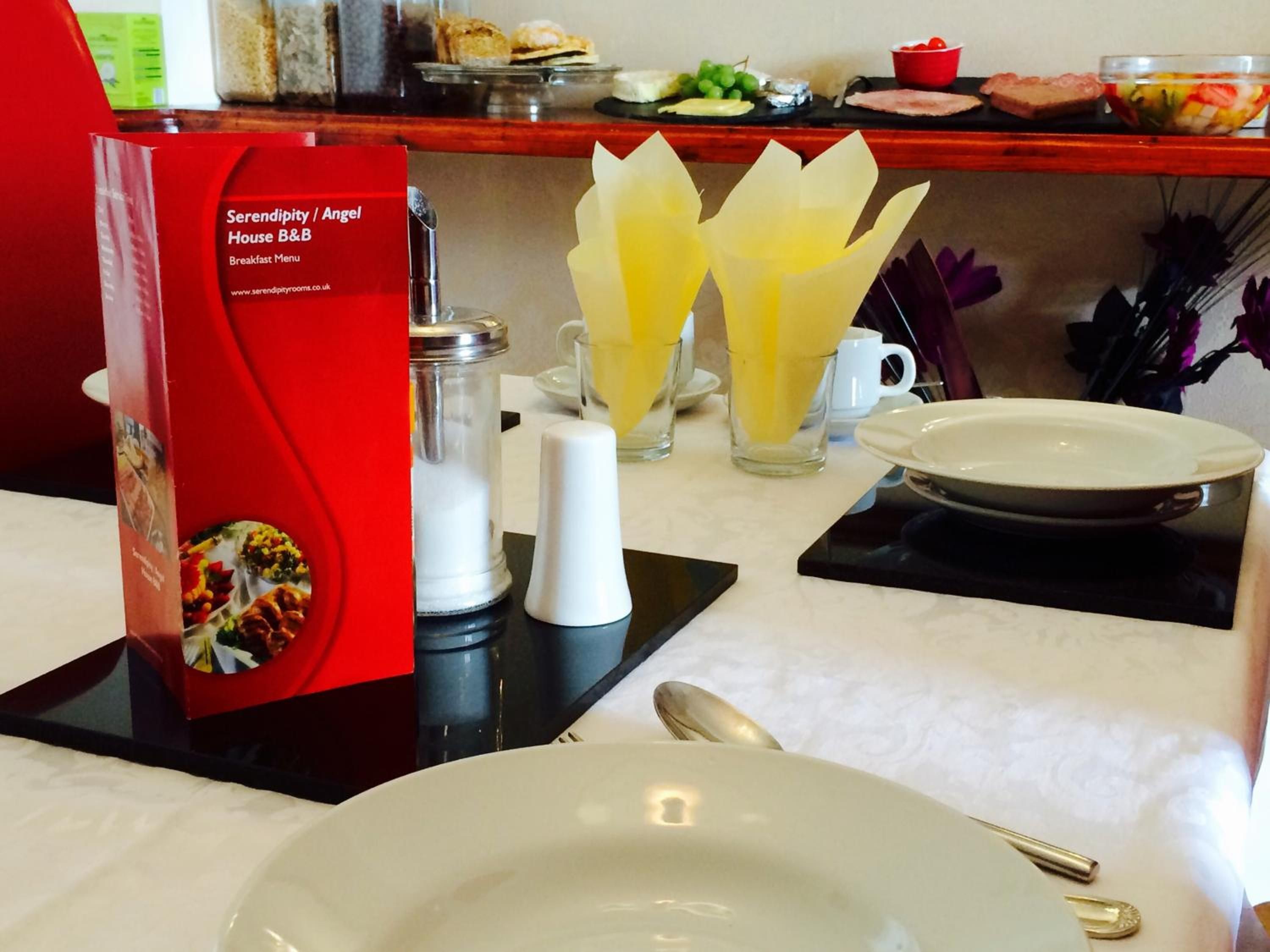 A breakfast setup with a menu, two glasses of orange juice, salt and pepper shakers, a plate, and a spoon.