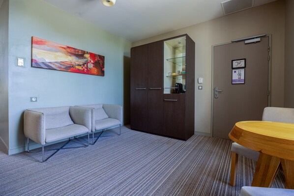 Habitación de hotel con sofá, una mesa de madera, armario y un cuadro en la pared.