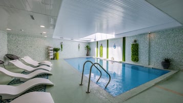 Una piscina techada, sillones reclinables de piscina