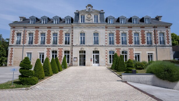 A large, historic building with a symmetrical facade, multiple windows, and a central entrance.