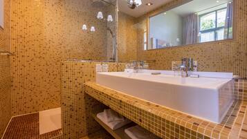A modern bathroom with a large sink, glass shelves, and a mirror.