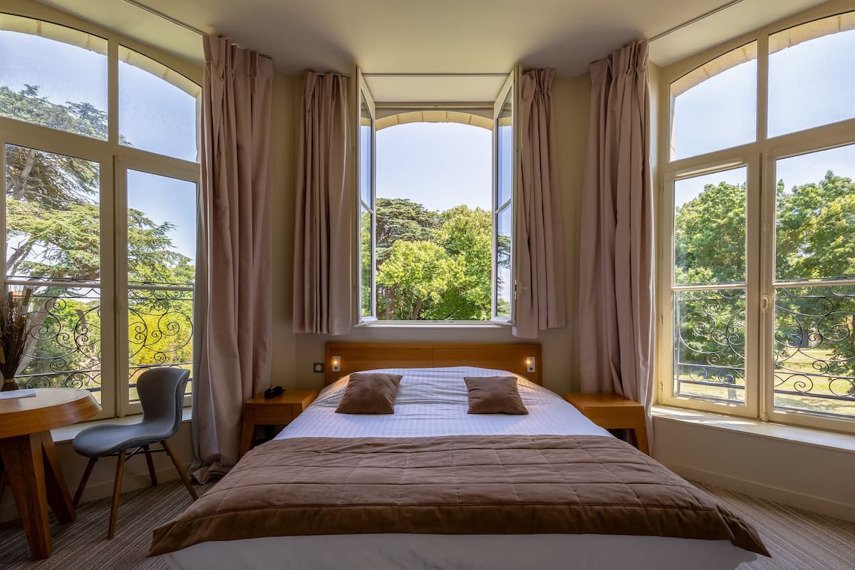 A bedroom with a large bed, two pillows, a desk, and a chair.