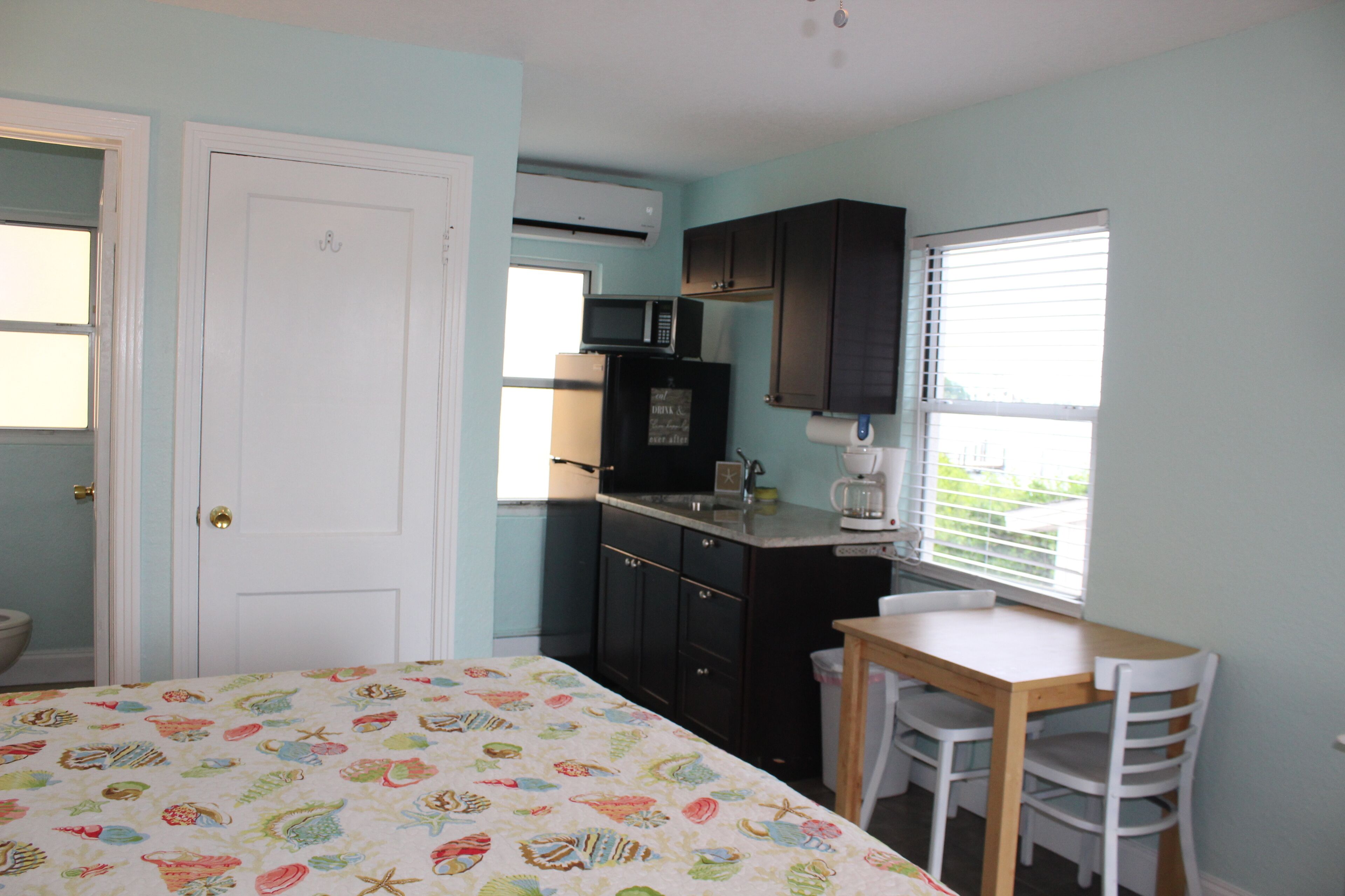 A bedroom with a bed, a small table, and a window.